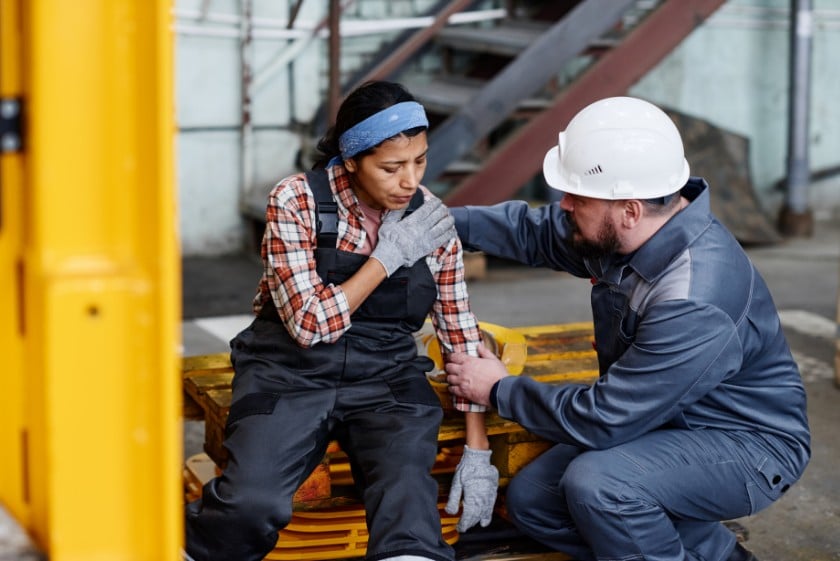 Woman sitting down at construction site holder her injured arm. Pennsylvania construction accident attorneys